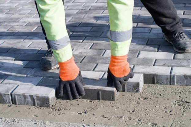 Concrete contractor placing brick pavers by hand for residential driveway installation in Chagrin Falls, OH