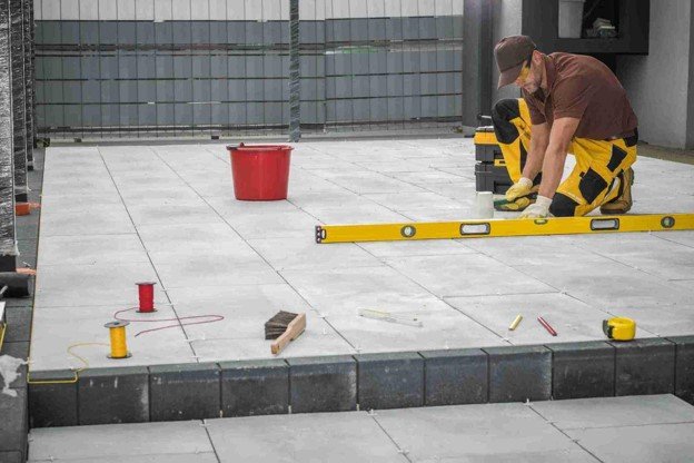 Contractor using a level tool to align large concrete patio slabs during installation in Chagrin Falls, OH