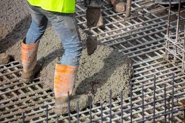 Worker pouring fresh concrete over steel rebar grid for structural slab construction in Chagrin Falls, OH